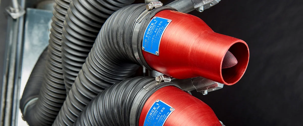 Red air cannons attached to black flexible hoses in an industrial setup.