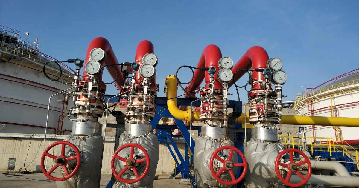 Compressed air piping system with red valves and pressure gauges at a facility.