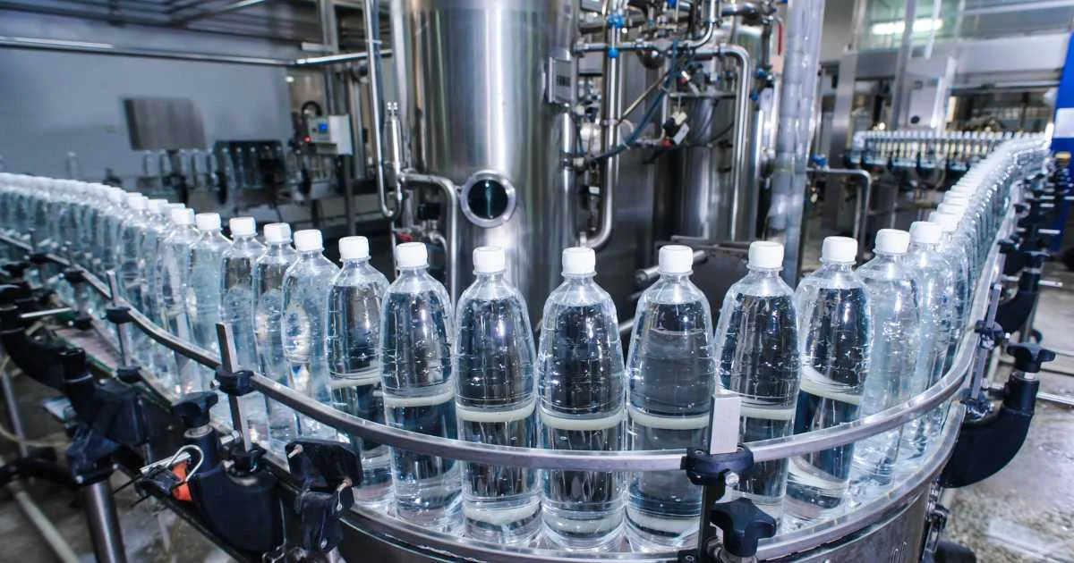 Plastic water bottles moving through an automated bottling line in a clean, modern manufacturing facility