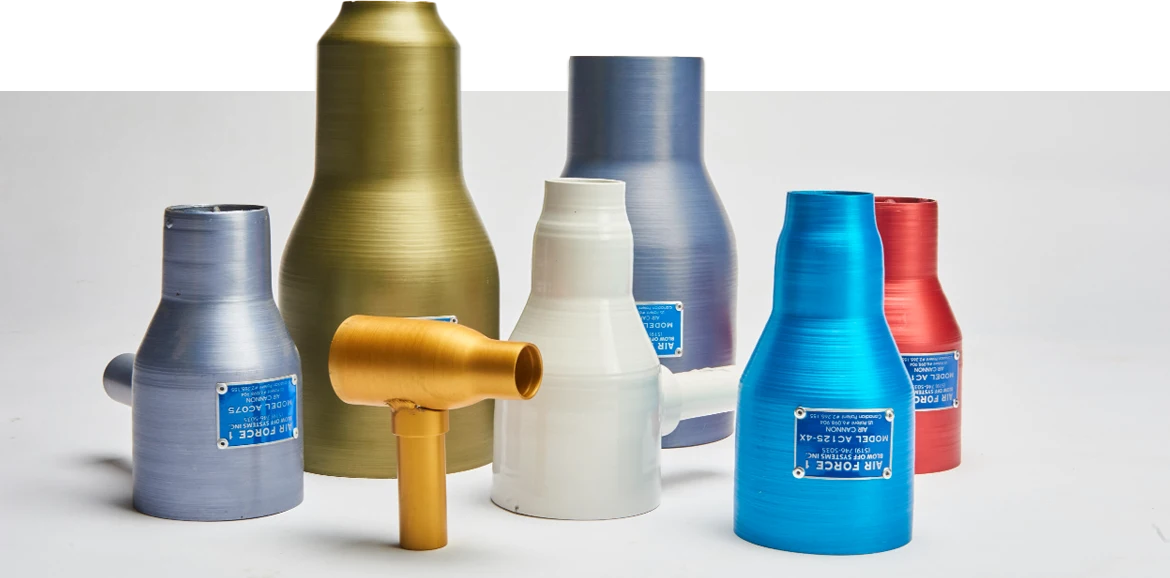 Various sizes and colours of industrial air nozzles standing upright on a white surface.