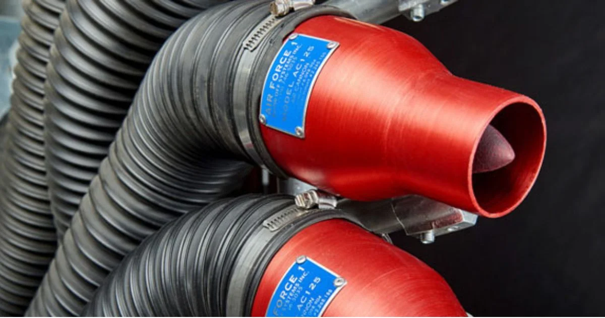 Close-up of red industrial air nozzles connected to black flexible hoses in a manufacturing setup