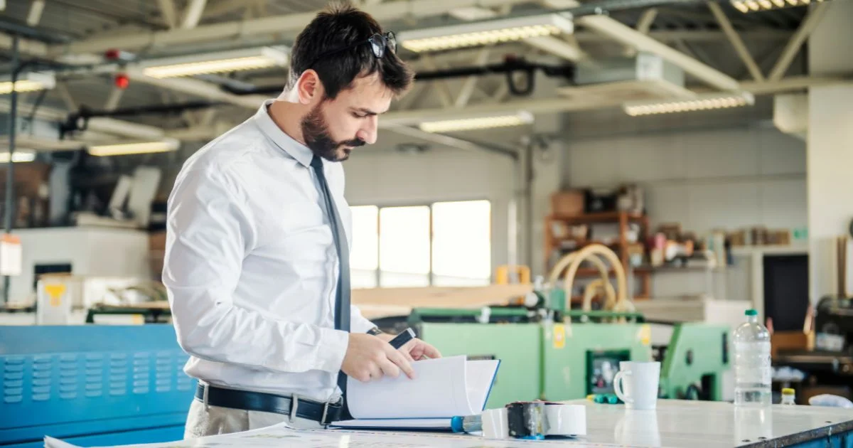 Engineer reviewing documents in factory workshop