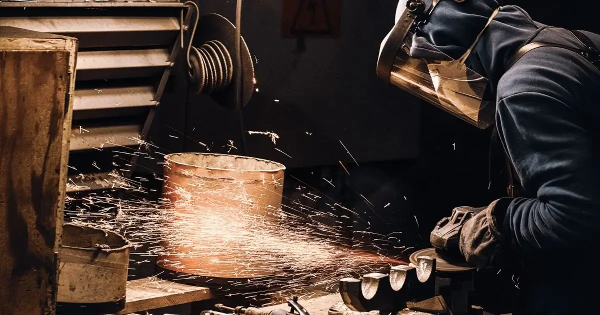 Worker grinding metal at industrial containment station